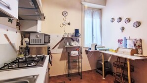 Eine kompakte Küche mit einem Gasherd, einer Mikrowelle und einer kleinen Kaffeemaschine auf einem Regal.