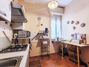 Ett kompakt kök med en gasspis, mikrovågsugn och en liten kaffebryggare på en hylla.