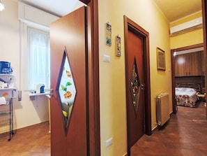 Un couloir avec des portes en bois, un radiateur et un lit à l’arrière-plan.