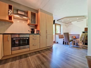 Eine moderne Küche mit integrierten Geräten, Holzschränken und einem Essbereich mit Tisch und Stühlen.