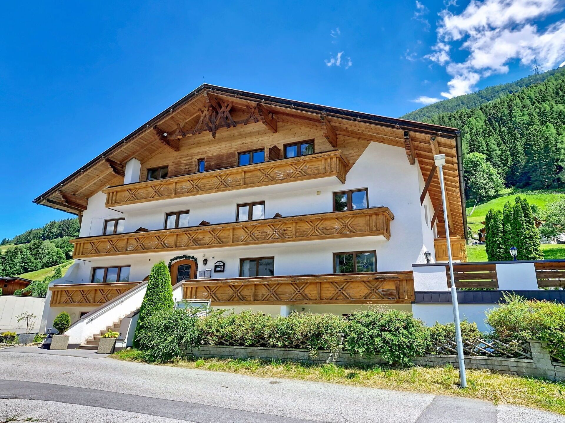 Ein mehrstöckiges Gebäude im traditionellen alpinen Stil mit hölzernen Balkonen und einer Treppe zum Eingang.
