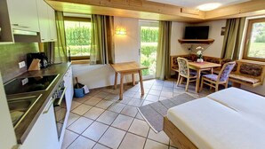 Ein gemütlicher Raum mit Küchenzeile, Essbereich, Sofa und Bett.