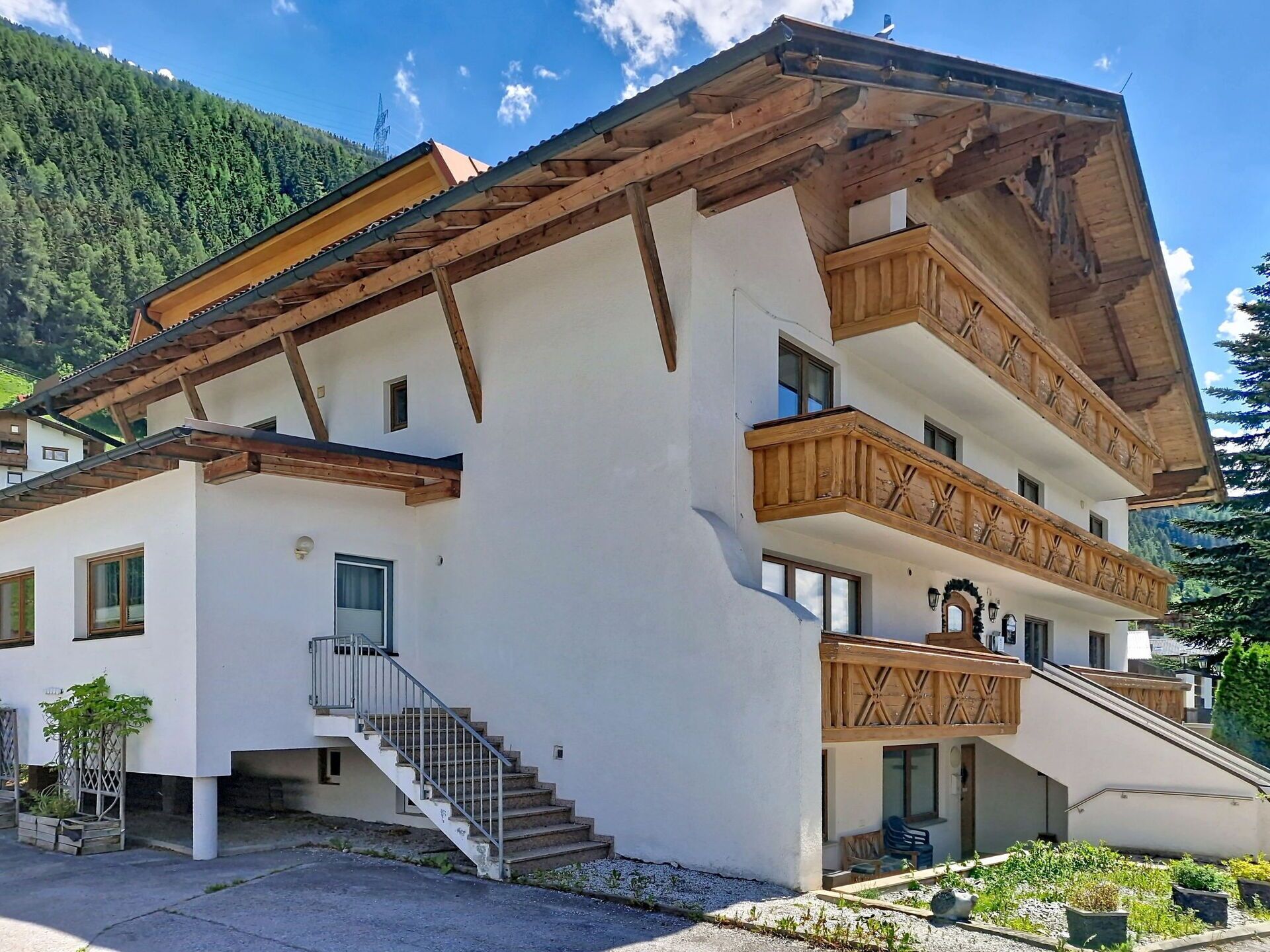 Ein mehrstöckiges Gebäude mit einem geneigten Dach, hölzernen Balkonen und einer Treppe, die zum Eingang führt.