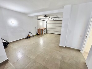 Une pièce spacieuse dotée d’un plancher carrelé, d’un ventilateur de plafond et d’un espace buanderie comprenant un lave-linge et un sèche-linge.