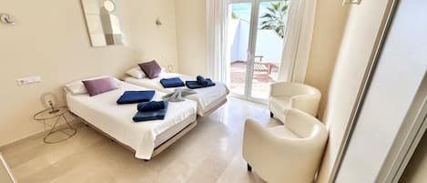 A hotel room with a bed, a chair, a small table, and a view of the outdoors.