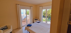 Ein Hotelzimmer mit Bett, einem Sessel und Blick auf den Balkon und die Außenlandschaft.