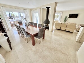 A spacious living area with a dining table, sofas, and a fireplace. - 5-Bedroom Villa with Panoramic Ocean View and Private Pool in Torrenueva, La Cala de Mijas (Las Lagunas de Mijas)