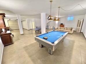 Une table de billard dans un salon moderne, avec un canapé et une lampe de table.