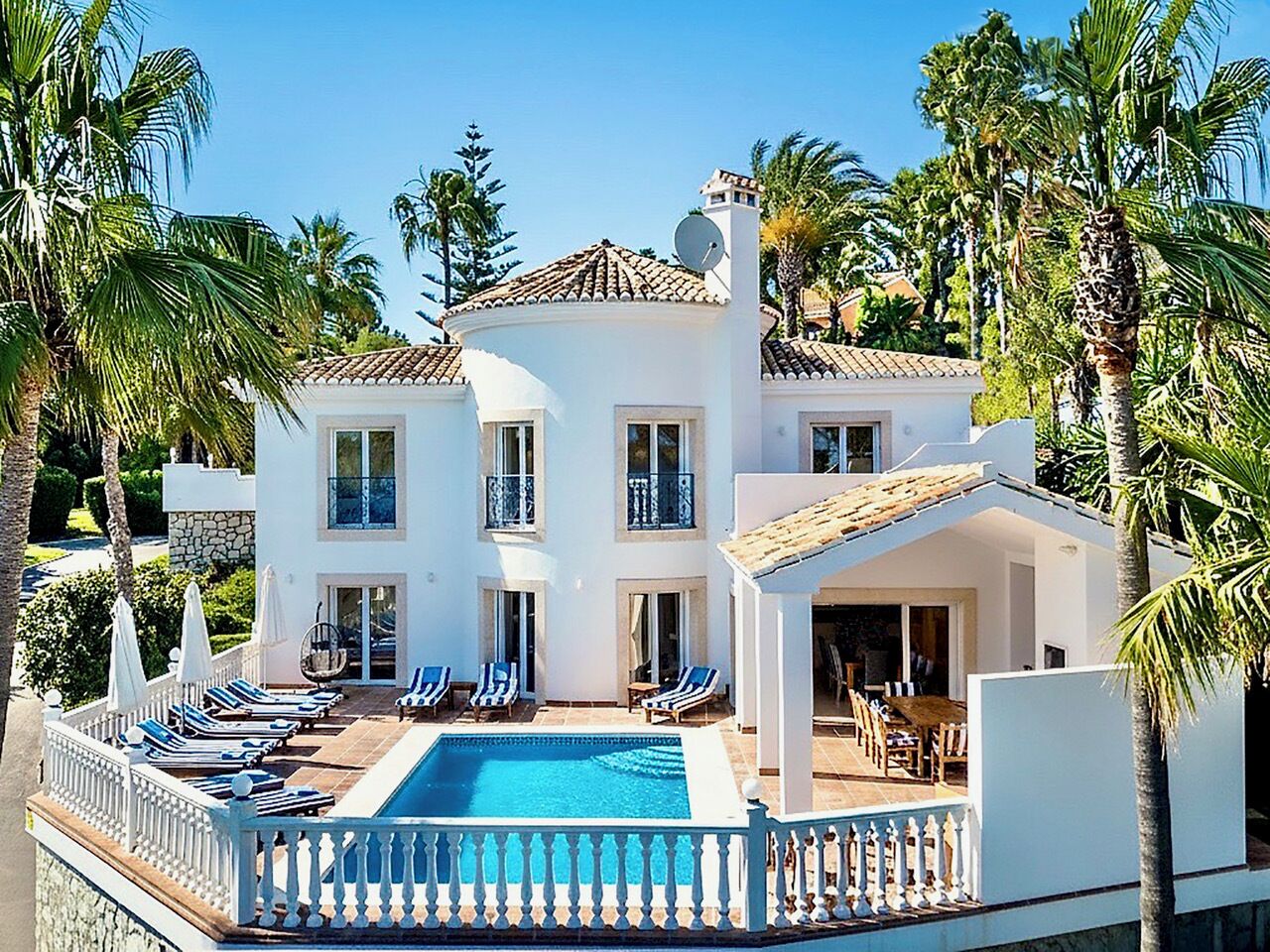 A two-story building with a swimming pool, multiple balconies, and a covered outdoor seating area.