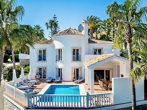 Ein zweistöckiges Gebäude mit Pool, mehreren Balkonen und einer überdachten Außenbereich-Sitzgelegenheit.