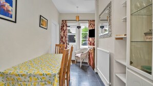 Une pièce comprenant une table à manger, des chaises, un radiateur, un téléviseur et un miroir.