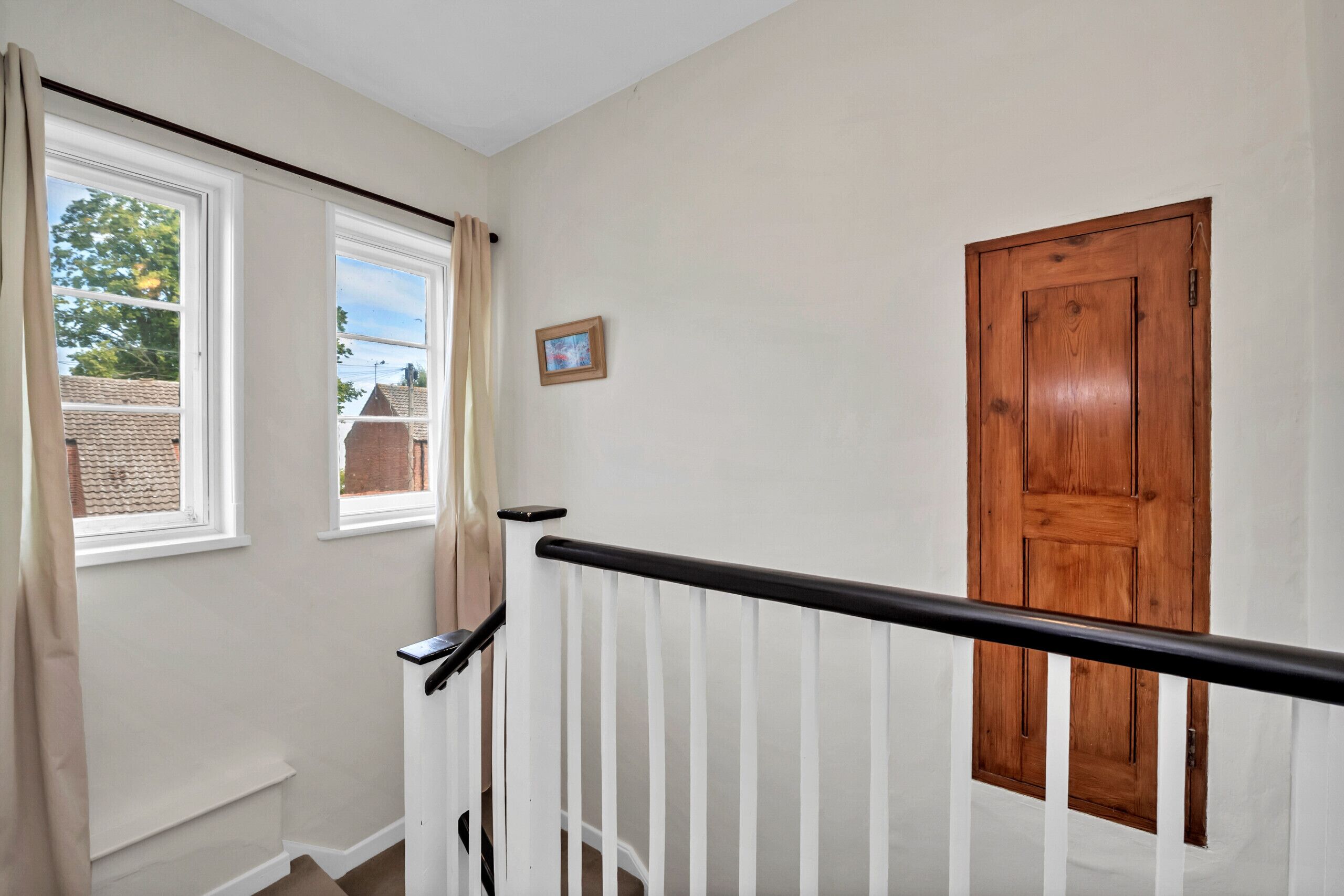A staircase with a wooden door and windows with curtains.