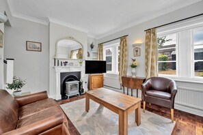 A living room with a fireplace, leather sofa, wooden coffee table, and a television. - The Jewel In Bury (Bury St Edmunds)