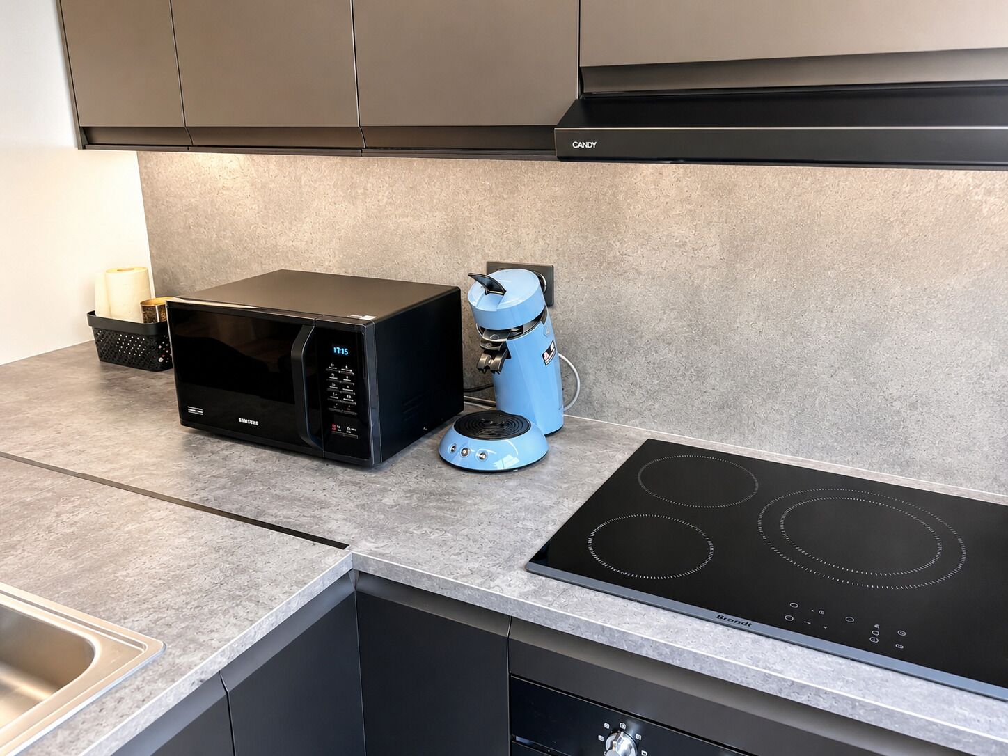 Une cuisine moderne équipée d’un four à micro-ondes encastré, d’une machine à café et d’une plaque de cuisson à induction.