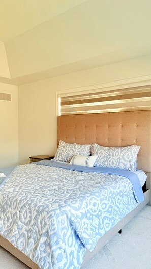 A bedroom with a bed, a headboard, and a bedside table.