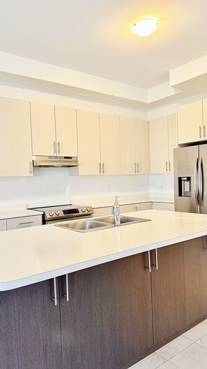 A modern kitchen with a central island, stainless steel appliances, and light-colored cabinetry. - Sleeps 14 | The Snow Valley Escape, Barrie | Entire House (Springwater)