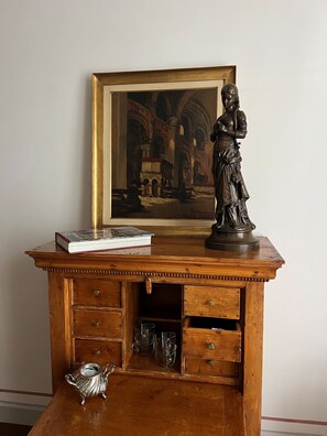 A wooden desk with a framed painting, a statue, and a book.