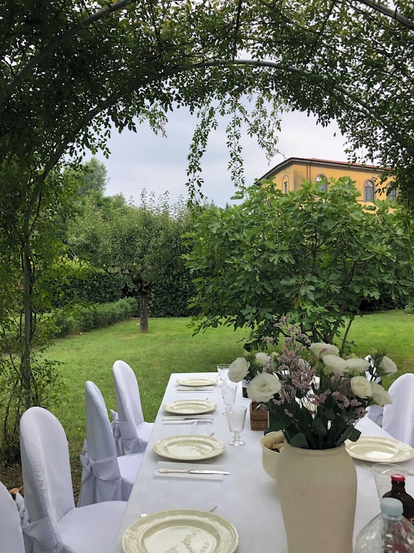 An outdoor dining area with a table set for four, surrounded by chairs, and a vase of flowers on the table.