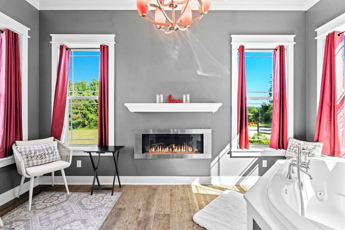 A modern living room with a fireplace, a sofa, a coffee table, and a view of the outdoors.