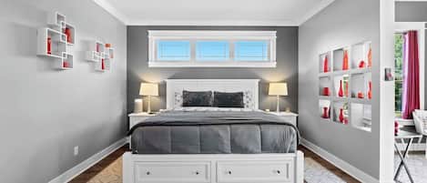 A bedroom with a bed, bedside tables, a ceiling fan, and built-in shelving with decorative items.