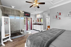 A modern bedroom with a large bed, a ceiling fan, and a glass shower enclosure. - 6BR Farmhouse Sleeps 14 | Fire Pit + Games + Trail (Traverse City)