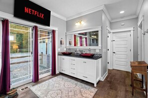 A modern kitchen with a large window, a Netflix sign, and a wooden side table. - 6BR Farmhouse Sleeps 14 | Fire Pit + Games + Trail (Traverse City)