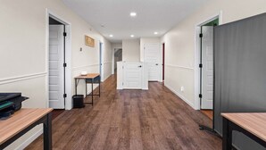 Um corredor com piso de madeira, portas brancas e uma pequena mesa com uma cadeira.