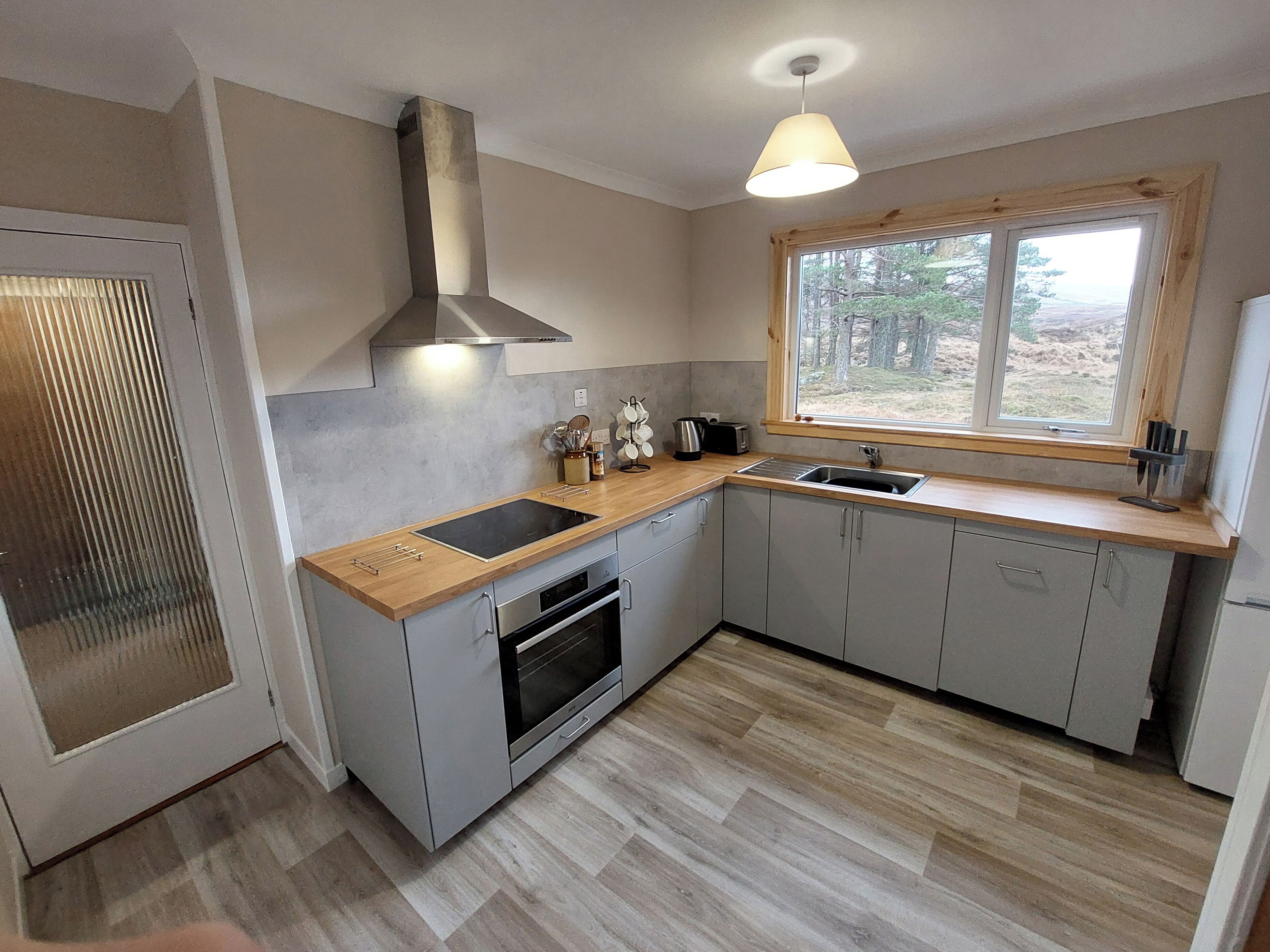 A modern kitchen with a built-in oven, a sink, and a window with a view of the outdoors.