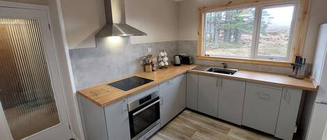 A modern kitchen with a built-in oven, a sink, and a window with a view of the outdoors.