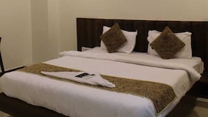 A hotel room with a bed, a ceiling fan, and a light fixture. - HOTEL ROSE PALACE (Surat)
