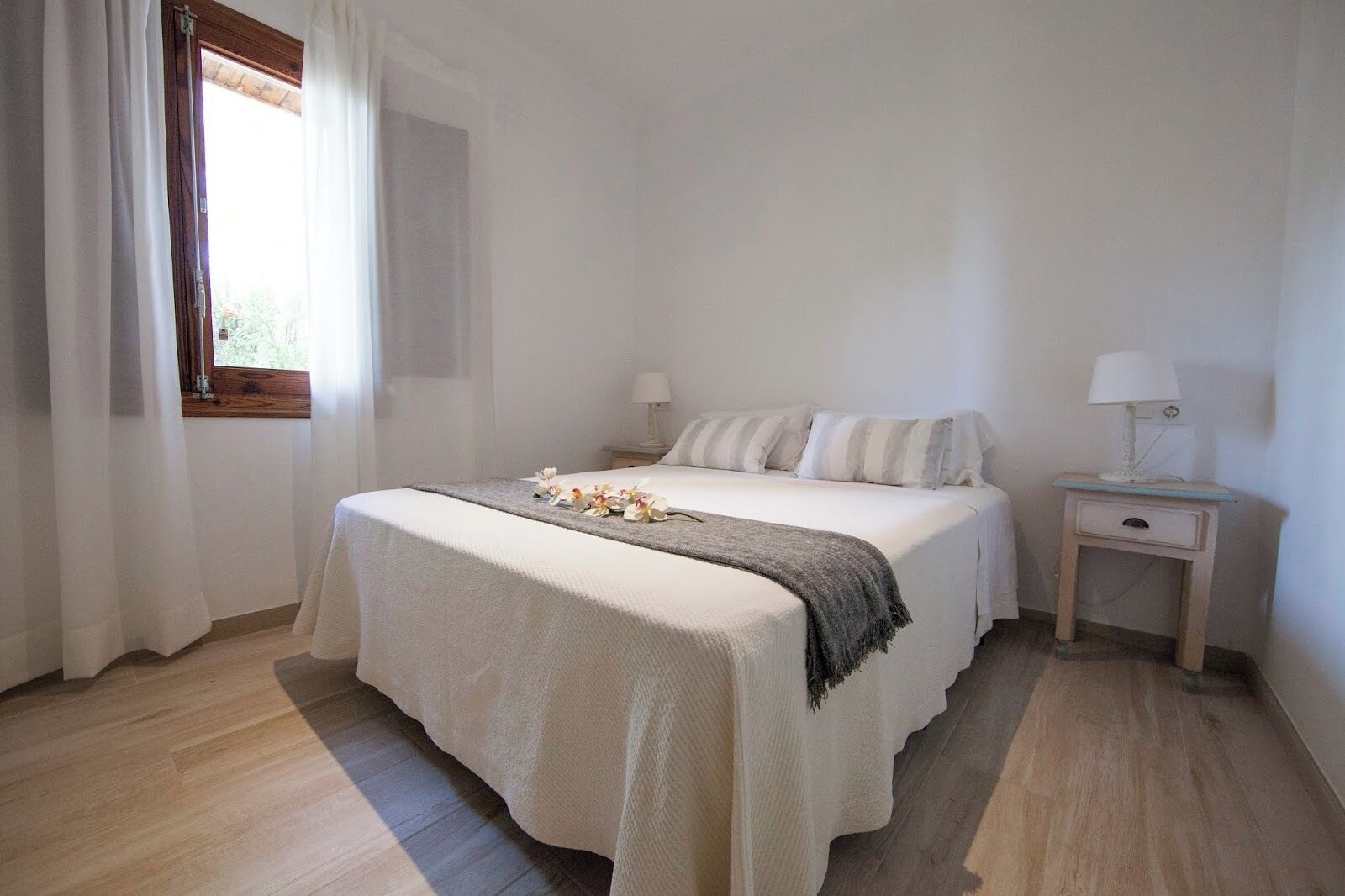 A bedroom with a bed, bedside tables, and a window with curtains.