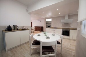 A modern kitchen with a round dining table, white cabinets, and a built-in oven. - Detached villa right on the sandy beach. Alcudia (Alcúdia)