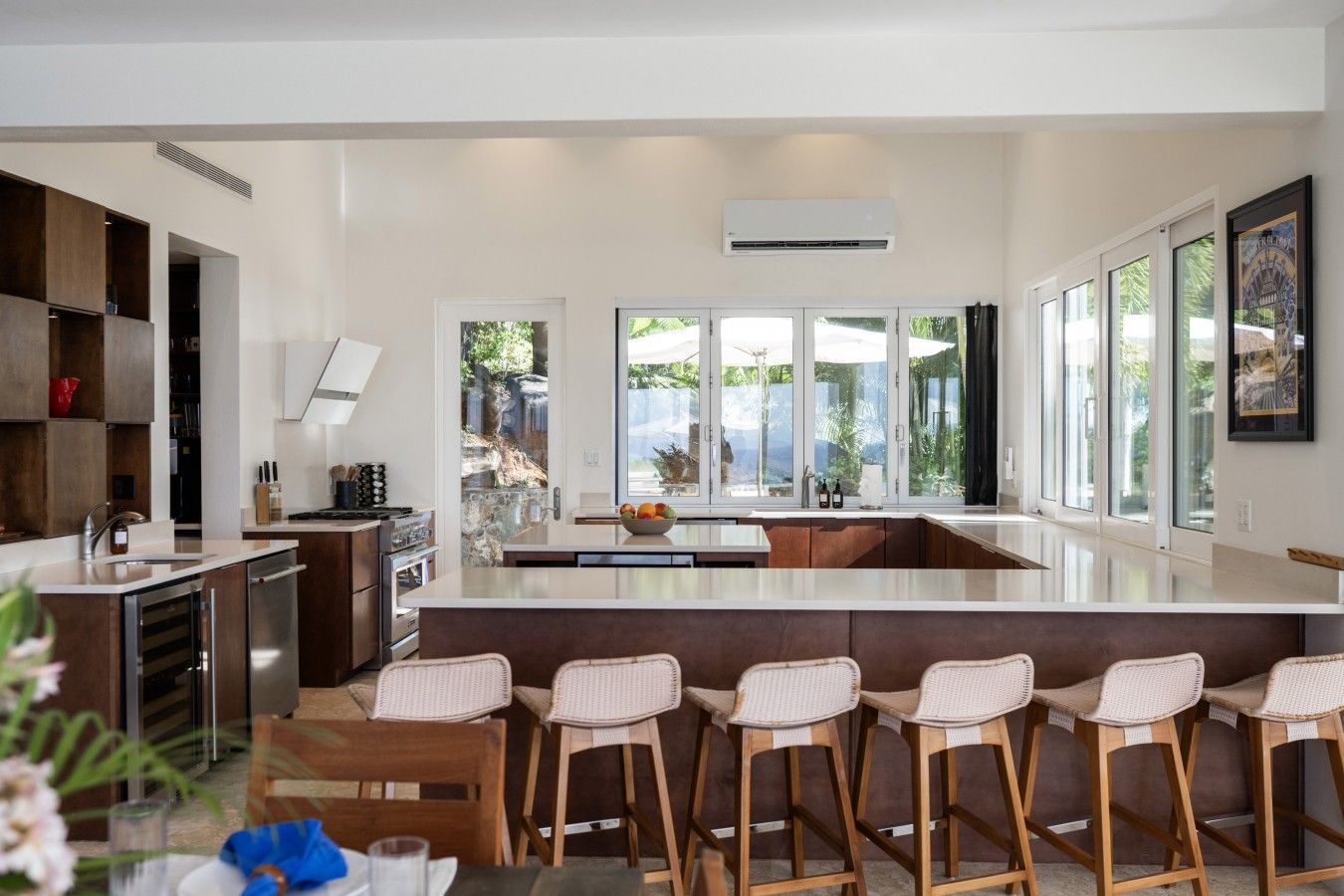 A modern kitchen with a large island, bar stools, and large windows.