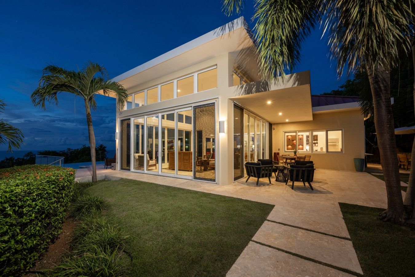 A modern house with a large glass door leading to an outdoor patio area.