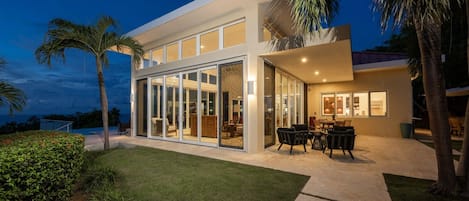 A modern house with a large glass door leading to an outdoor patio area.