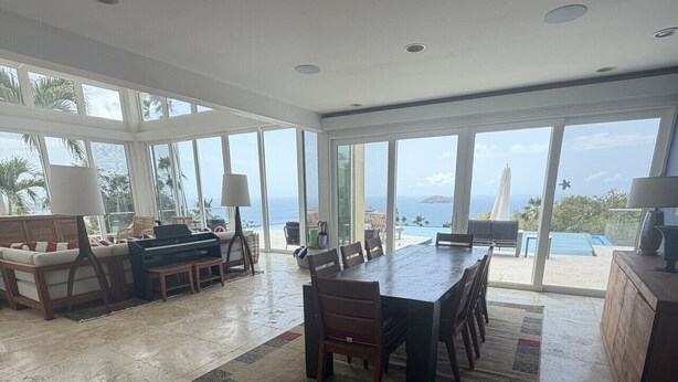A spacious living area with a large dining table, seating, and a view of the ocean.
