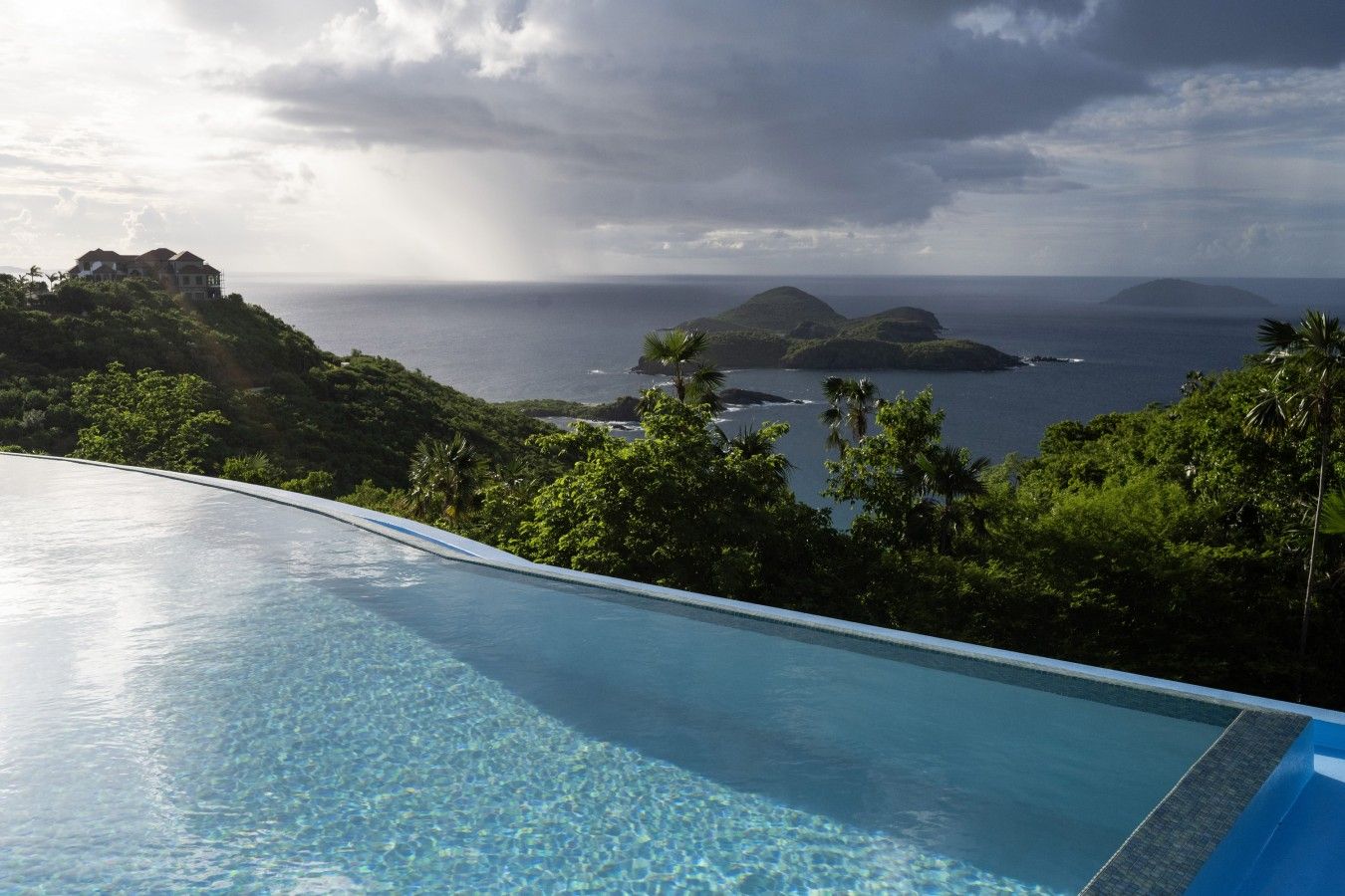 A pool with a view of the ocean and hills.