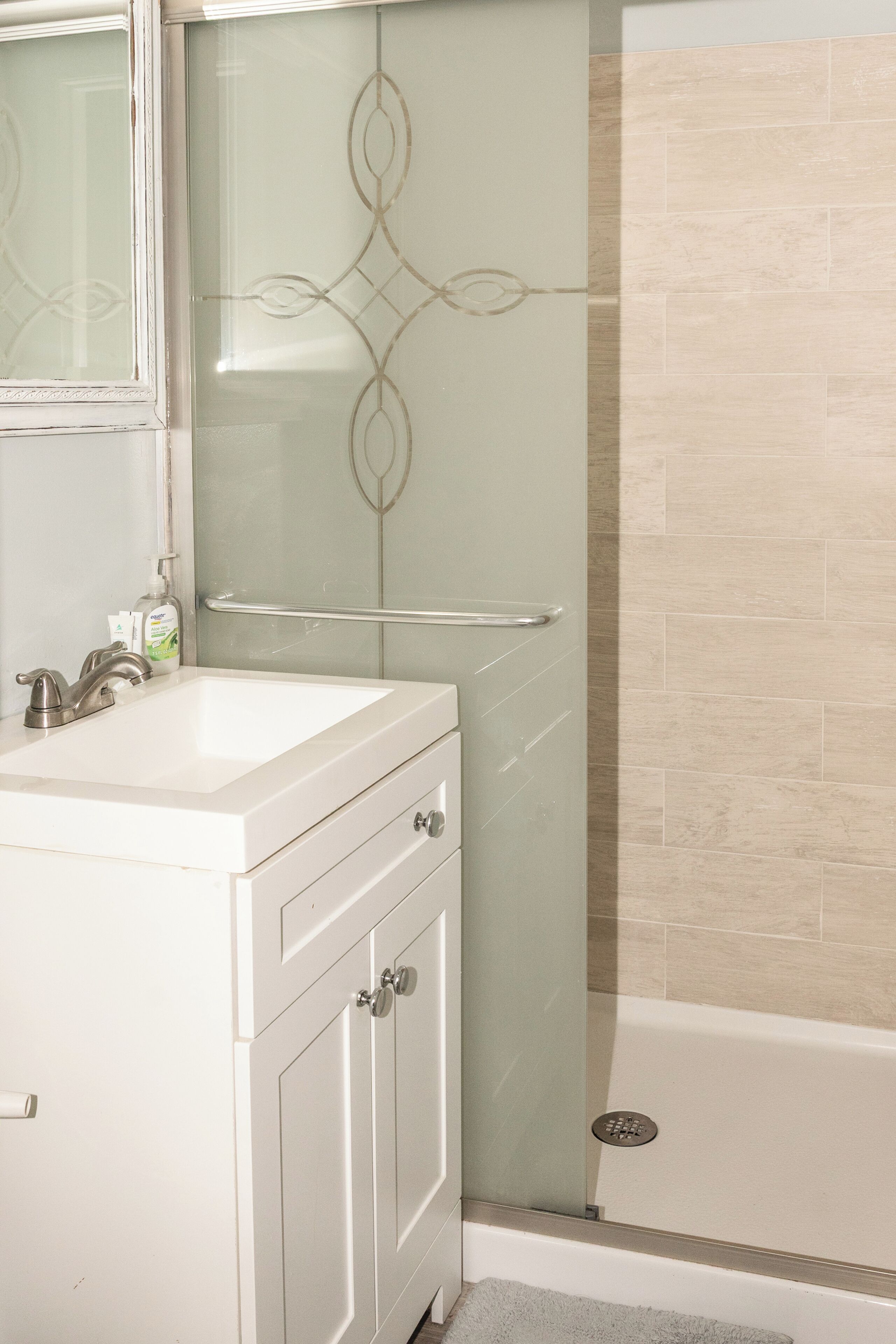 A bathroom with a white vanity, a glass shower enclosure, and a bathtub.