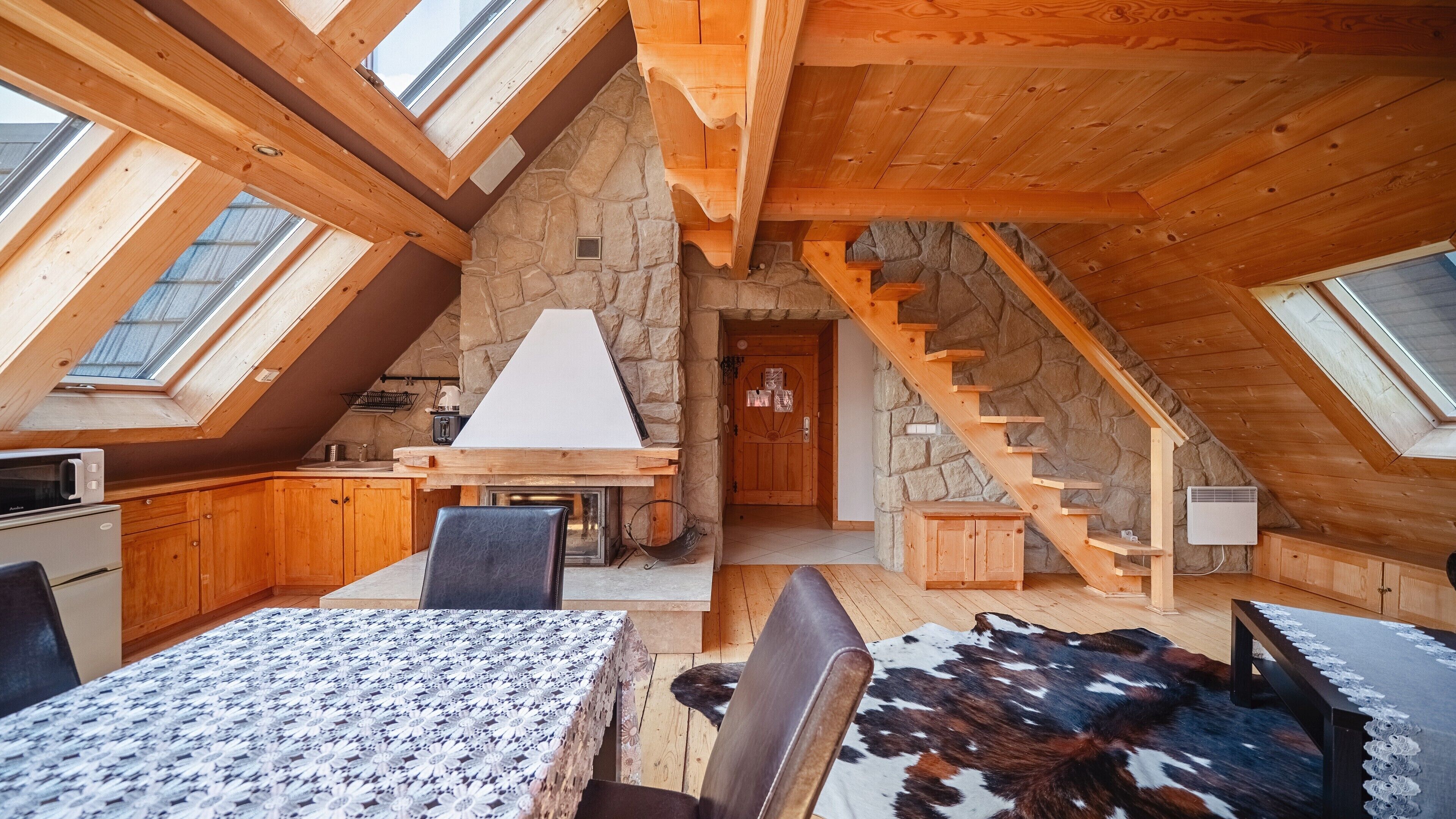 Ein gemütliches Schlafzimmer im Dachgeschoss mit Steinwand, einer Holztreppe und Dachfenstern.