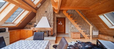 A cozy attic bedroom with a stone wall, wooden staircase, and skylights.