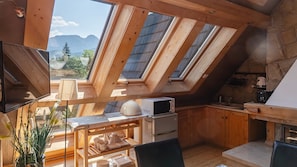 A kitchen with wooden cabinets, a microwave, and a stove. There is a skylight above the kitchen. - Apartamenty Sun & Snow Butorowy  (Kościelisko)