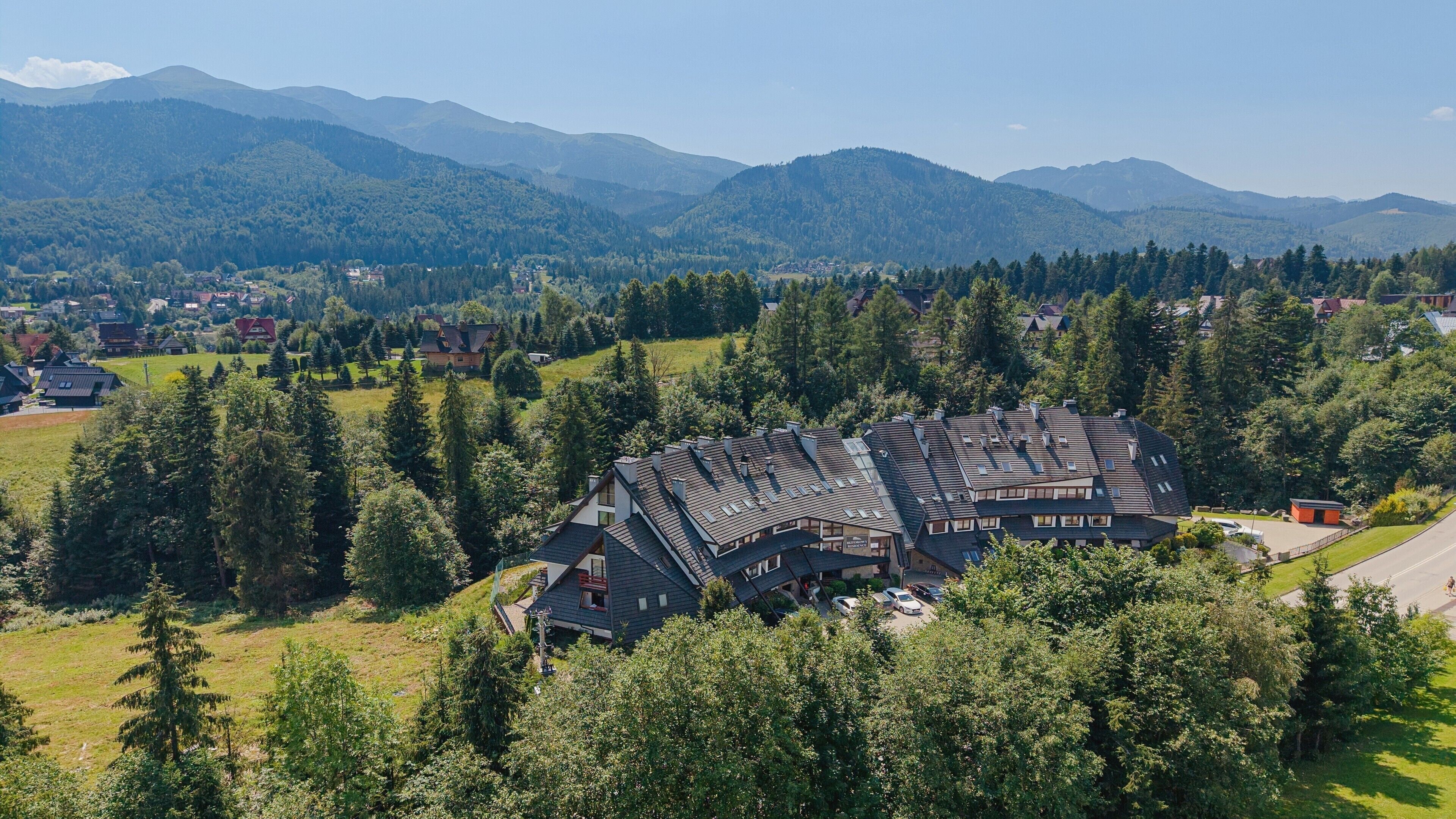 A mountain village with traditional houses surrounded by forest and mountains.