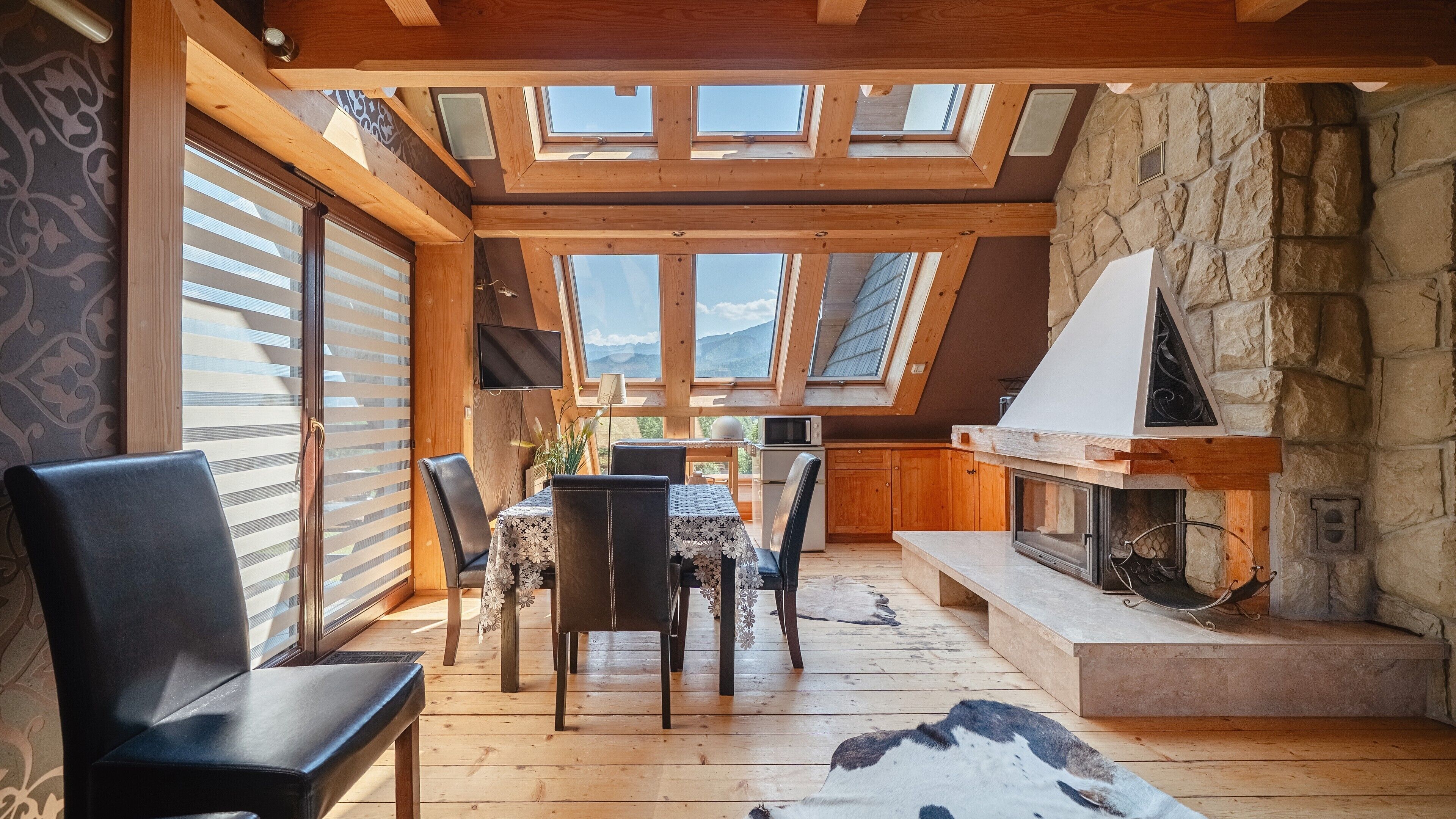A cozy interior with a dining area, a fireplace, and a stone wall.