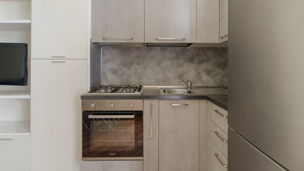 Una cocina moderna con horno empotrado, estufa a gas y pileta de acero inoxidable.