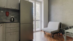 Cocina compacta con refrigerador, hervidor y ventana con vista a árboles.