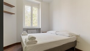 Una cama individual con sábanas blancas y una ventana encima.