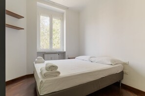 Ein Einzelbett mit weißer Bettwäsche und einem Fenster darüber.