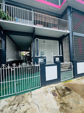 A two-story building with a balcony, a gated entrance, and a small window. - Trendy Beach Escape w/ 2 Kings (Carolina)