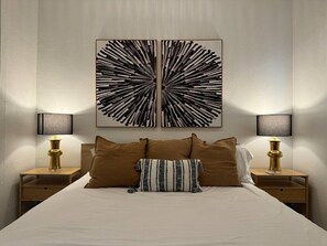 A bed with a headboard, two bedside tables, and two wall-mounted lamps. - Trendy Beach Escape w/ 2 Kings (Carolina)