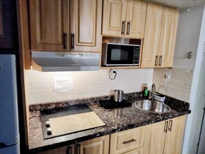 Eine Küche mit Holzausstattung, einer Mikrowelle, einem Spülbecken und einer Arbeitsplatte mit einer Fußmatte.